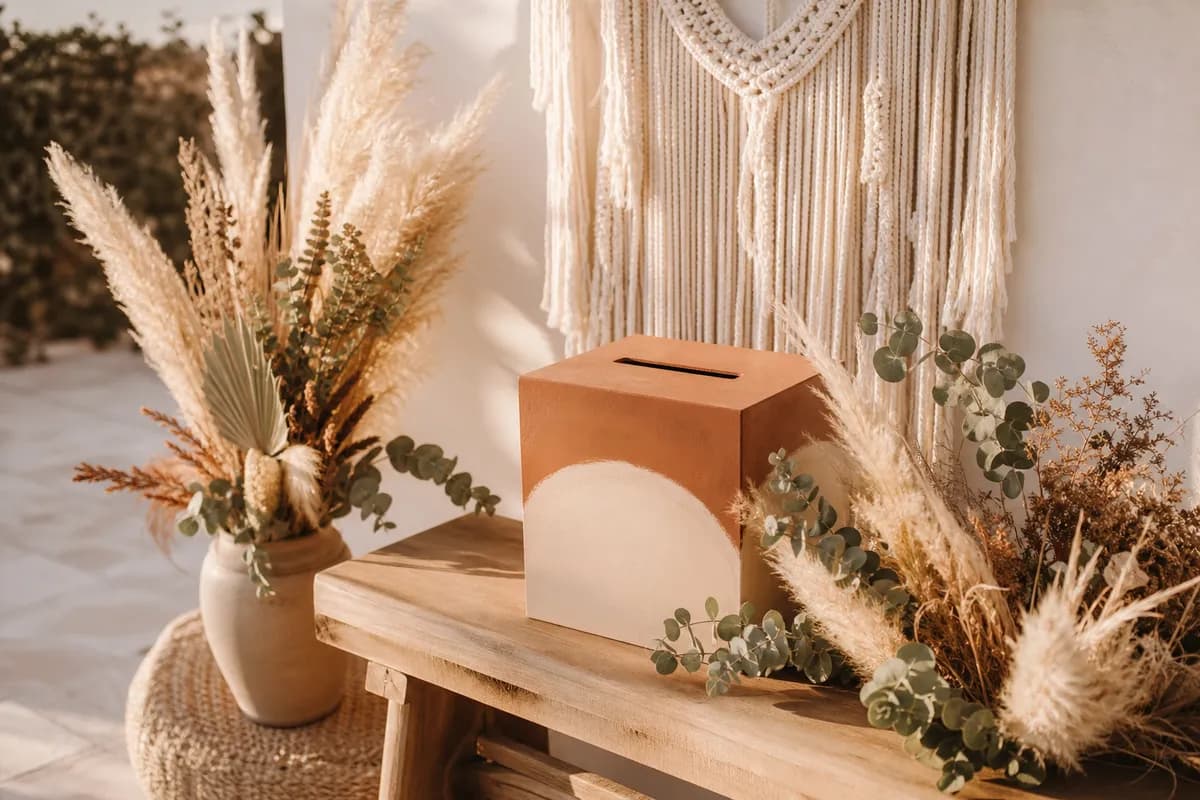 Rincon boho de lluvia de sobres con pampas, eucalipto y macrame sobre banco de madera clara