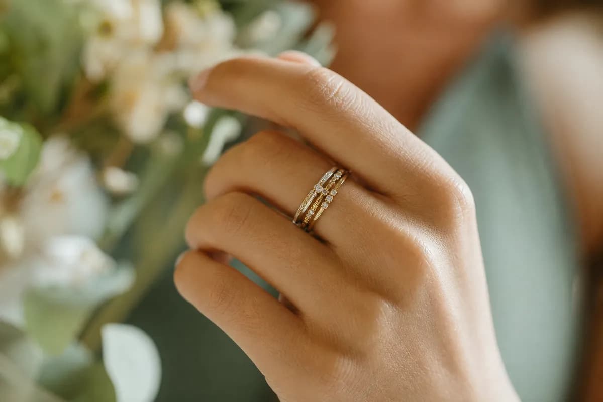 Set de anillos apilables en plata y oro con pequenas piedras en un dedo, estilo moderno