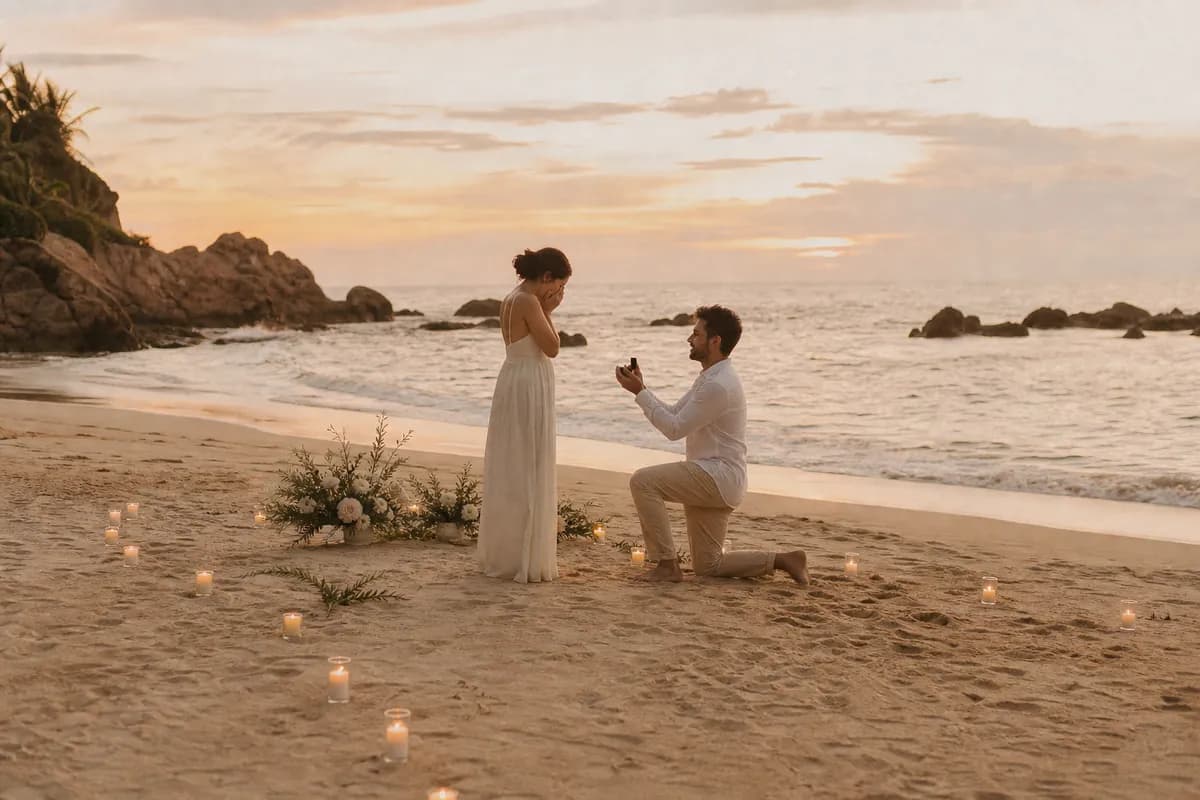 Pedida de matrimonio en playa mexicana con camino de velas sobre la arena al atardecer